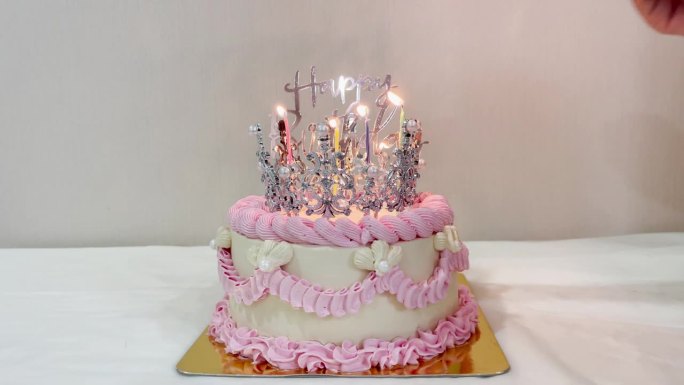 女人的手点燃蜡烛，祝生日快乐，蛋糕上有美丽的银冠