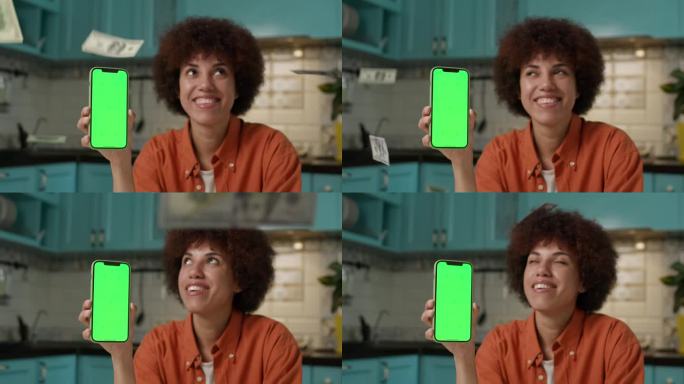 女性手中的绿屏手机上的美元。黑人女性展示彩色键智能手机，现金在慢镜头中掉落。