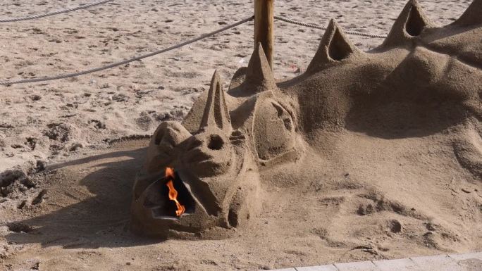 建造喷火龙形状的沙雕。火从沙龙口燃烧