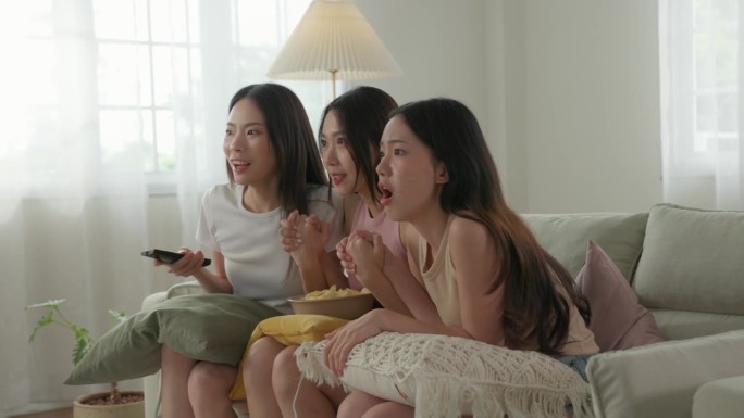 激动的亚洲年轻成年女性在电视上庆祝获奖