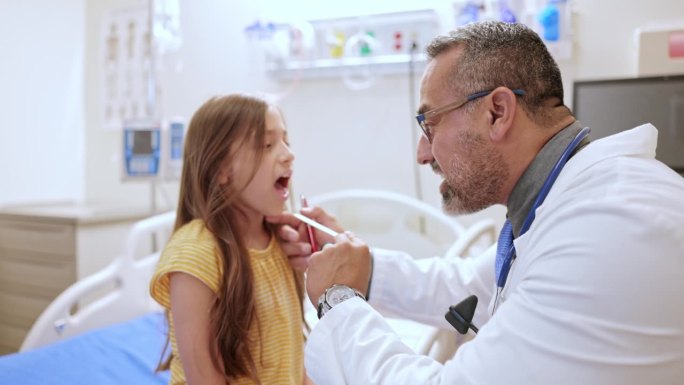 医生用压舌板和手电筒检查一个9岁女孩的口腔