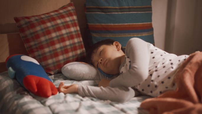 可爱的韩国男孩在阳光明媚的儿童房的床上醒来的肖像。超级可爱的孩子准备好了一个充满冒险的阳光明媚的一天