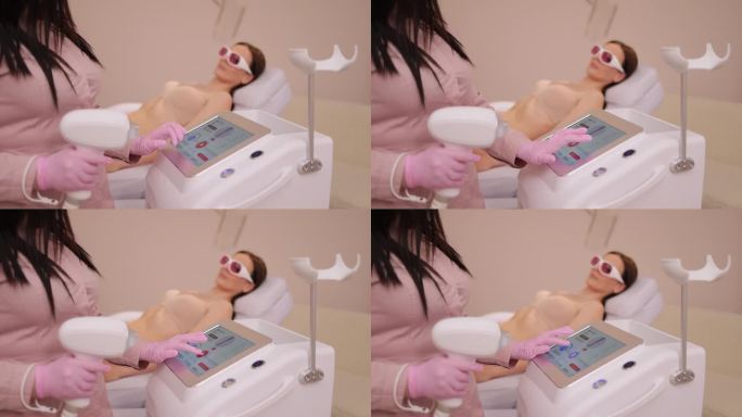 女美容师在美容院使用激光脱毛机。美容院医师检查激光脱毛机