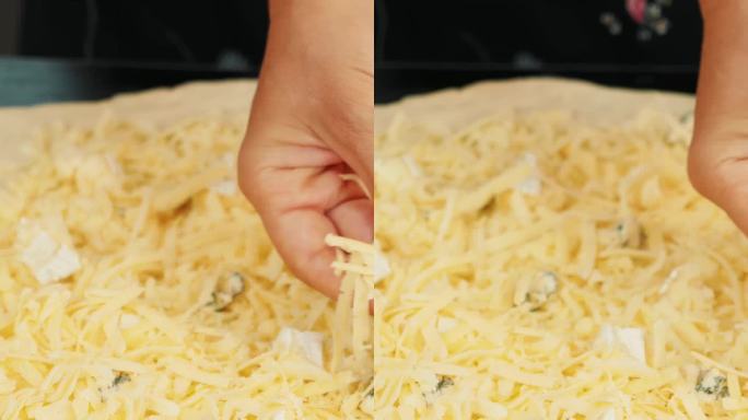 女性的手在披萨上撒碎奶酪的特写。垂直视频
