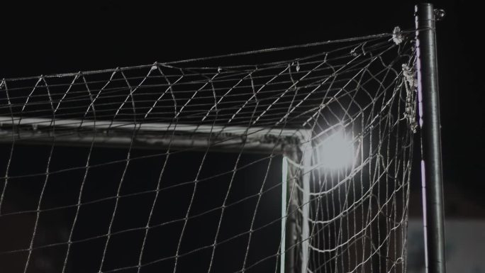 在晚上的足球比赛中，球门的顶角的背面。英式足球比赛。体育场聚光灯下的照明弹和灯光。体育的概念。近距离