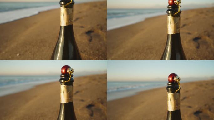 在日出的海边，一瓶打开的香槟，在瓶口上放着一个红色的装饰品，一个圣诞节的装饰品。