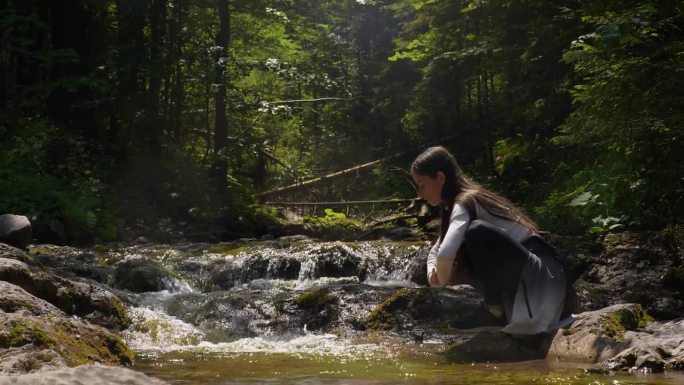 美丽的年轻长发女子或女孩洗脸，在森林山的河里取水。塔特拉国家公园，波兰扎科帕内。
