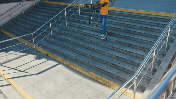 非裔美国人扛着自行车走下楼梯