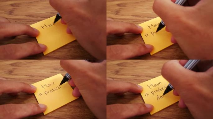 励志视频语录有一个富有成效的一天!一个人在一张木桌上写了一张黄色的纸条。除了花瓶里的绿色植物装饰。