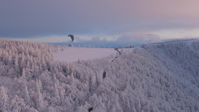 从空中拍摄的滑翔伞，飞过冬日的风景