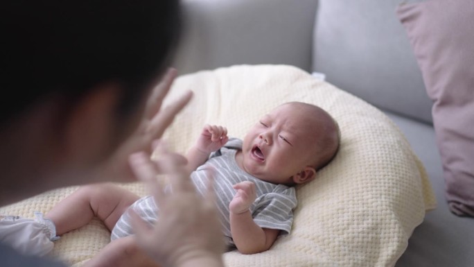 妈妈在家里沙发上的婴儿床上和宝宝玩耍