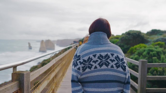 年轻的女性旅行者在澳大利亚维多利亚州的“十二使徒”向外眺望大海