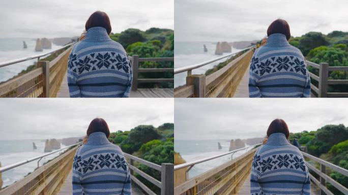 年轻的女性旅行者在澳大利亚维多利亚州的“十二使徒”向外眺望大海