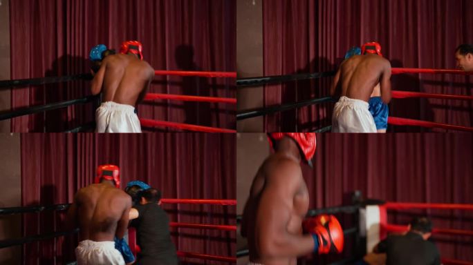 非洲年轻的成年拳击手带着拳击手套装，在拳击台的turnbuckle上狠狠地击打着非洲年轻的成年拳击手