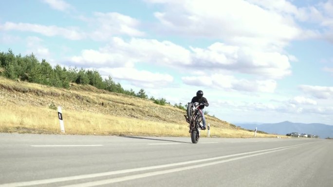 特技骑手在摩托车后轮上表演特技，这是极限运动