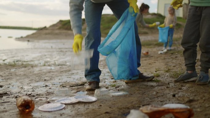 志愿者家庭在岸上收集塑料垃圾，父子共同努力，生态安全