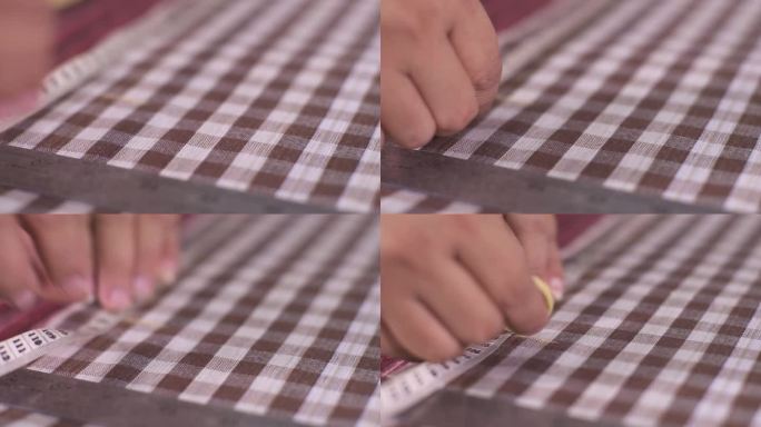 女裁缝正在用卷尺量格子布的尺寸，并在上面画上点，以便裁剪。