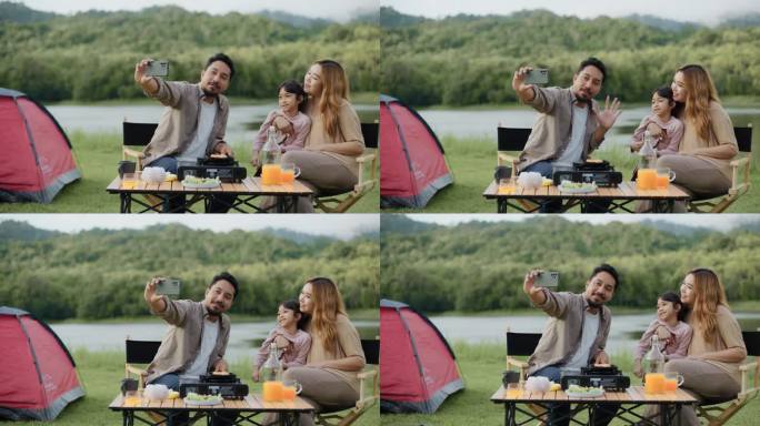 幸福的一家人在湖边的露营地用照相手机自拍。