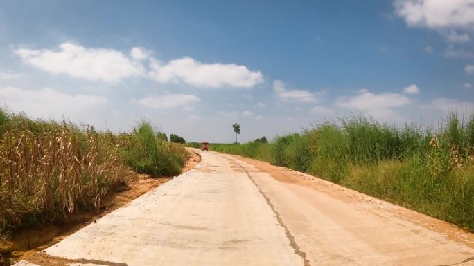 在土路上奔跑的视角。越野车的车轮行驶在尘土飞扬的肮脏道路上，湿的和干的泥。在穷乡僻壤旅行的观点