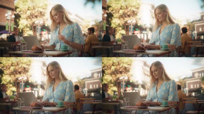 美丽的女人在夏日舒适的咖啡馆露台上使用笔记本电脑。金发碧眼的年轻女子在一个蓝色的连衣裙与花卉图案喝咖