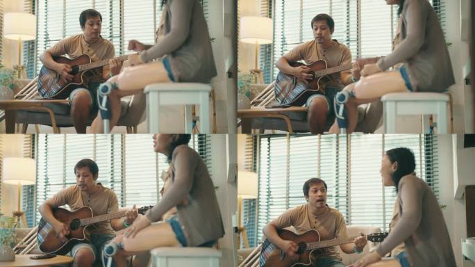 幸福的残疾夫妇享受并乐于花时间在家里弹吉他和唱歌。冷静的态度。积极情绪。残疾人。