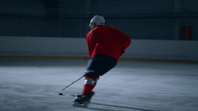 熟练的冰球运动员在冰场上用冰球棍射击、击球和击打冰球。运动员用电影般的灯光和戏剧性的广角镜头得分