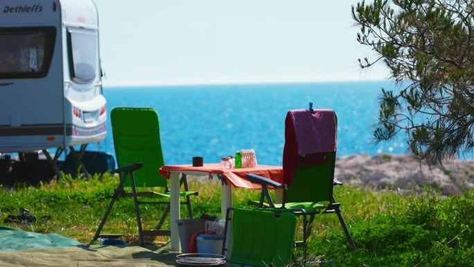 SLO MO椅子和桌子由汽车之家在阳光明媚的日子-周末旅行。在海滩上浪漫的露营，可以看到大海