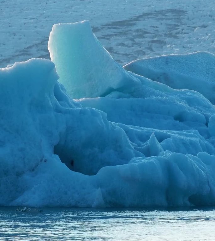 竖屏:北极的纯蓝冰。冰岛的冰山从冰川中分离出来。清澈的蓝冰漂浮在蓝绿色的海水中。为社交媒体拍摄。杰古