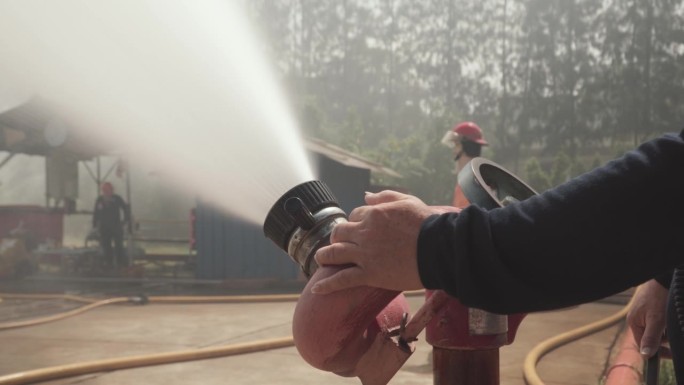 消防队员使用灭火器和软管中的水灭火。