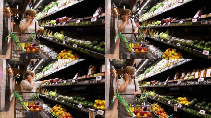 成熟的女人推着购物车购物，一边打电话一边从超市的冷藏区拿蔬菜