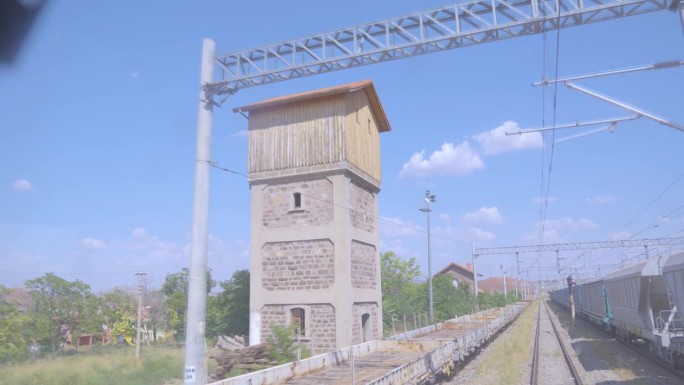 在偏远的农村地区，白天缓慢到达干线货运列车的4K镜头。砖和木塔从机车司机的角度看POV股票视频。