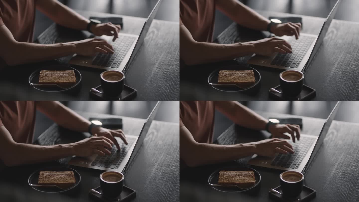 在咖啡馆用笔记本电脑工作的男子，近距离观察在键盘上打字的年轻男子的手