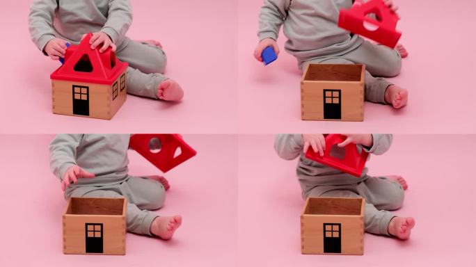 快乐的蹒跚学步的婴儿在工作室粉红色的背景上玩几何形状的分类器。小男孩玩益智玩具。孩子一岁八个月，身高