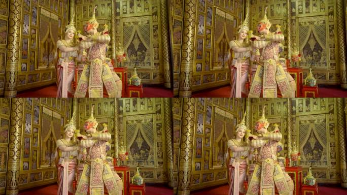 泰国经典的蒙面男子从拉玛金角色带着红色面具与美丽的亚洲女人跳舞，穿着泰国传统服装，呆在公共场所墙上的
