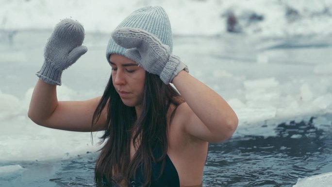 女人在冰天雪地里冬泳。潜入水中