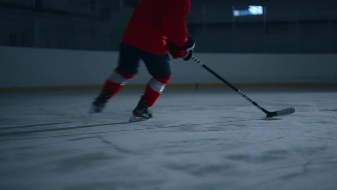 动态视频的曲棍球运动员在红色球衣熟练地移动在溜冰场，避免障碍和得分的目标与精度