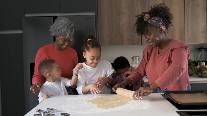 一个非洲家庭在玩面粉，用擀面杖把曲奇面团擀出来。