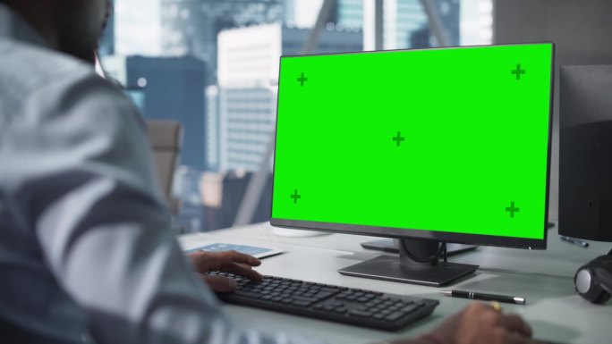 过肩镜头近距离电脑屏幕与绿色模拟模板。匿名男子在办公室工作，浏览互联网，并在网上搜索商业数据