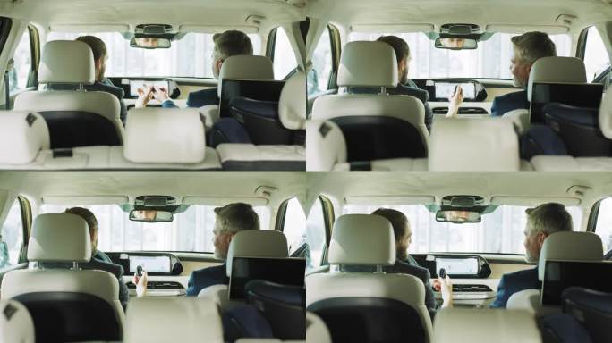 男性朋友坐在汽车后座的后视图。一位快乐的顾客坐在他新买的车里，从一个专业的成熟的销售员手里接过车钥匙