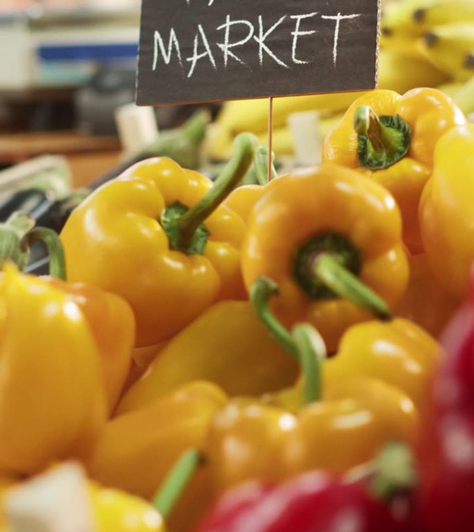竖屏:农贸市场生态蔬果大排档。有机红色和黄色灯笼椒，新鲜茄子，生物香蕉和其他杂货在户外摊位上的标志