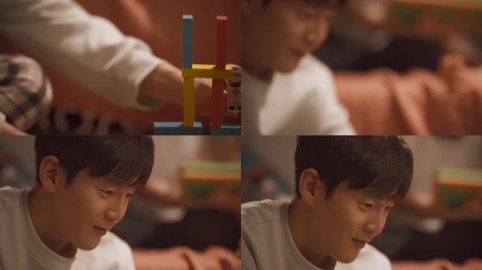 一个年轻的韩国男人和他的孩子在家里玩积木的特写。英俊的父亲把一个宇航员小雕像放在一个建造好的玩具大楼