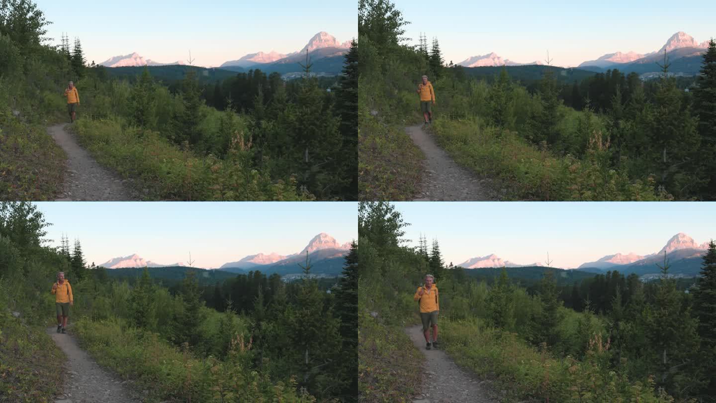 老人在黎明时分沿着山路徒步旅行