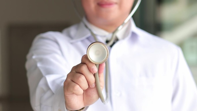 亚洲医生手持听诊器，暗示是时候进行体检了，医护人员，专业的医疗服务理念。