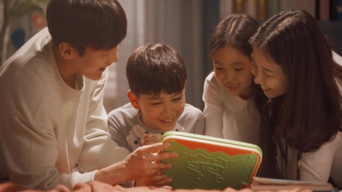 年轻美丽的韩国家庭一起在家里度过闲暇时光，在网上看动画片，和他们的天才孩子一起在平板电脑上玩教育电子