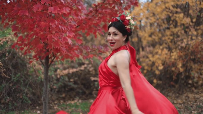 一位身穿红裙、头戴花圈的女士在表演秋舞。秋天公园里的女孩。