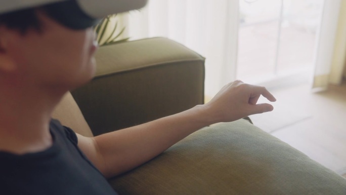 坐在客厅里玩虚拟现实技术的人专注于移动双手。