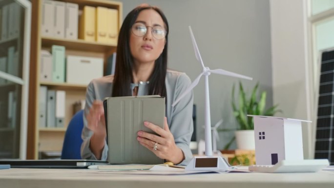 女工程师在办公室看风力发电机模型和使用平板电脑