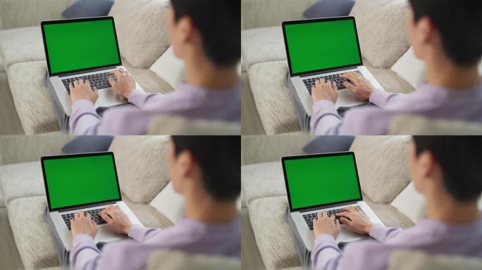 在一个匿名的男性从舒适的家里工作的镜头，使用绿色屏幕模拟显示的笔记本电脑无缝地管理任务和项目