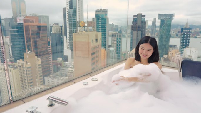 一名女子在屋顶的极可意热水浴缸中放松，俯瞰香港的高楼大厦。