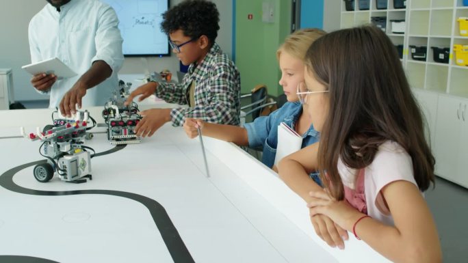 幼儿和老师看着机器人模型在桌子上移动